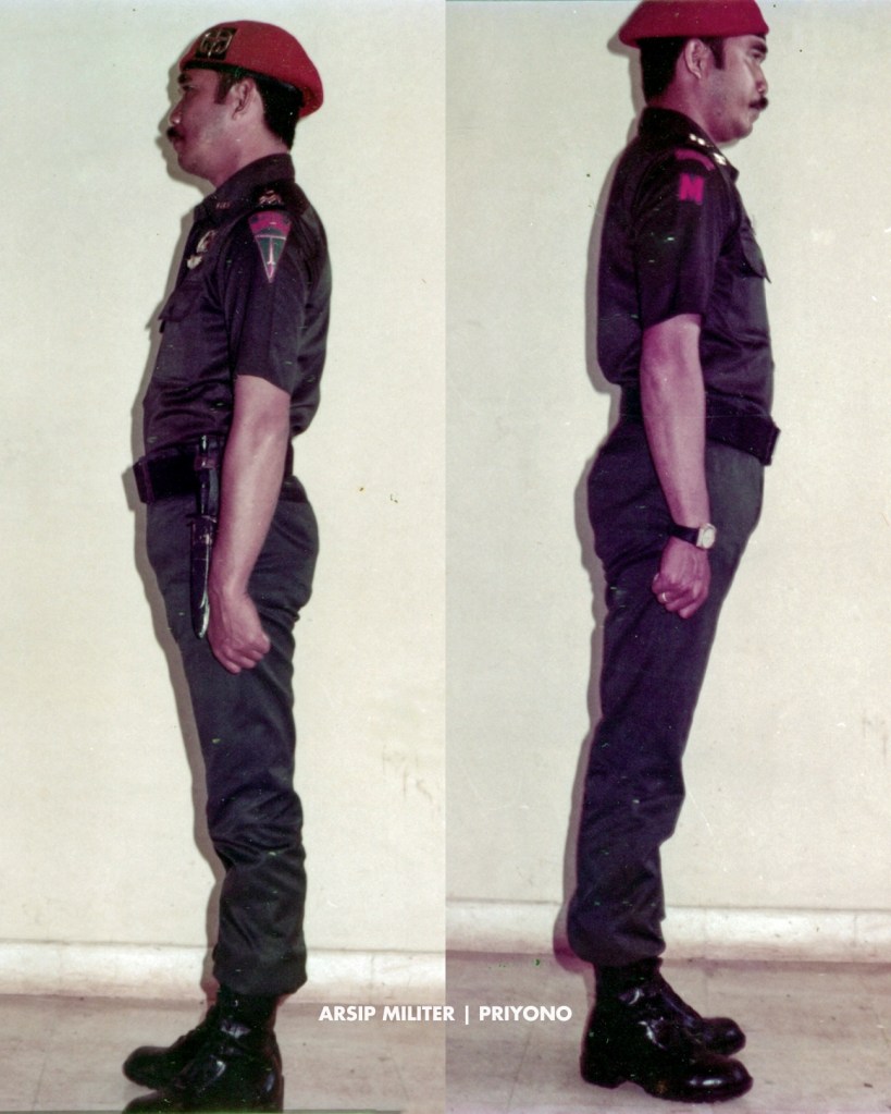 PDH hijau lengan pendek dengan baret KOPASSANDHA, brevet Komando dan wing terjun pinned, plat nama, 

Patch Para-Komando di lengan kiri, serta patch “MARKAS” dan scroll “KOMANDO” di lengan kanan.